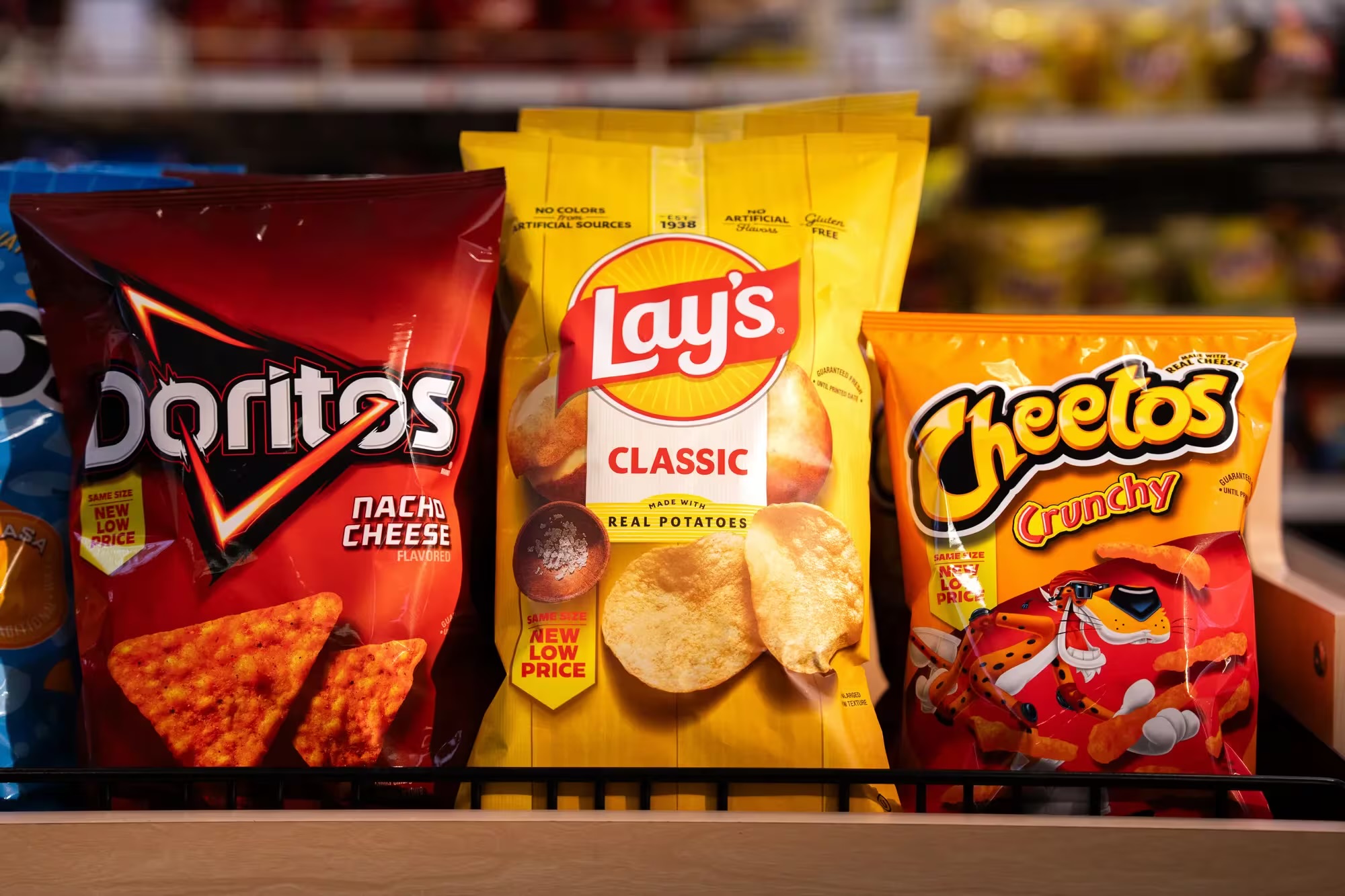 Assorted dry snack packages including chips, crackers, and granola bars